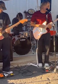 a group of people playing guitars under a tent