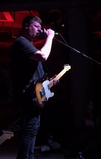 a man singing into a microphone while playing guitar
