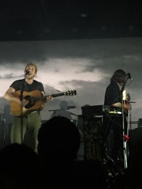 two men on stage with guitars and microphones