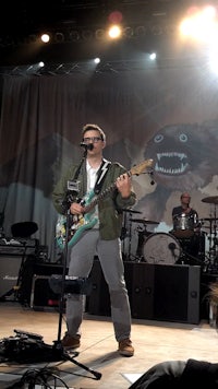 a man standing on stage with a guitar