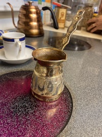 a coffee pot on a counter next to a cup of coffee