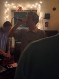 a group of people in a room singing into a microphone
