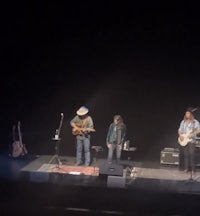 a group of people standing on stage with guitars